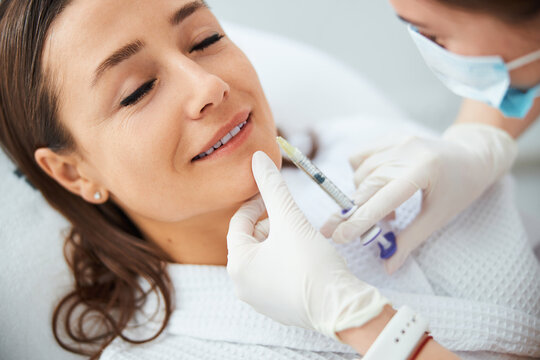Pleased dark-haired woman getting an anti-wrinkle injection