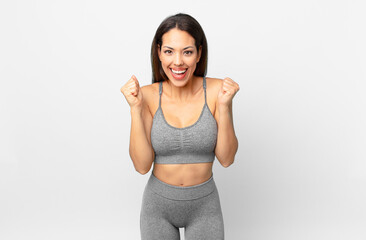 young hispanic woman feeling shocked,laughing and celebrating success. fitness concept