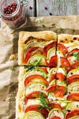 homemade puff pastry pie with zucchini and tomatoes on a light wooden background. Vegetarian, healthy food, comfortable food, homemade food, proper nutrition, farm food concept.