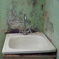 Old sink with a faucet on the background of dirty walls