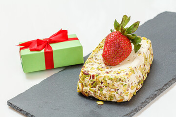 Halva with pistachios and strawberry on stone cutting board