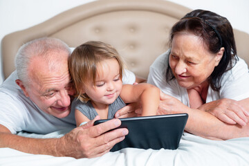 Seniors with a baby are looking at a tablet