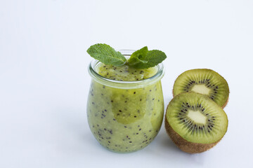 Fototapeta na wymiar Kiwi smoothie or puree in the glass jar on the white background. Close-up.