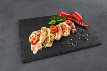 Chilled meat for barbecue with vegetables on a board on a dark background 