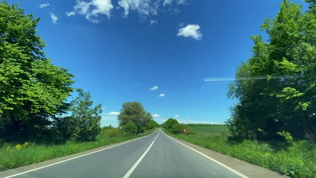 Driving on empty asphalt road with white markings on a sunny summer day
