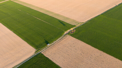 Fototapeta premium Aerial view of the tractor spraying the chemicals on the large green field. Great shadows.