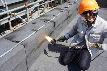 Flat roof installation with propane blowtorch during construction works with roofing felt. Heating...