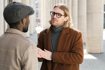 Two colleagues talking to each other while meeting on the street