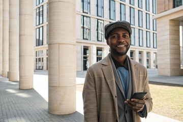 Portrait of African young businessman smiling at camera while standing in the city