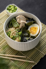 asian ramen soup with chicken and egg noodles. with the addition of fresh onions on a dark copyspace background, For menus and articles with recipes