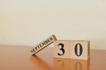 September 30, Date design with calendar cube on wooden table and white background.