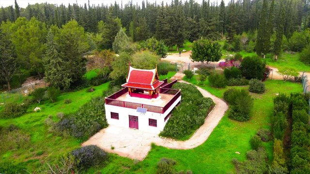 Aerial Panning Shot Of Thai Pagoda By Pathway, Drone Flying Over Green Trees In Ben Shemen Forest