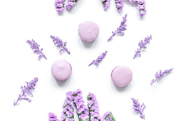 macaroons and flowers for light breakfast on white desk background top view