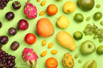 Many different delicious exotic fruits on green background, flat lay