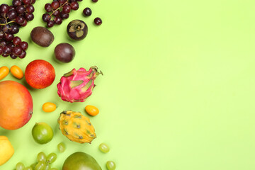 Many different delicious exotic fruits on green background, flat lay. Space for text