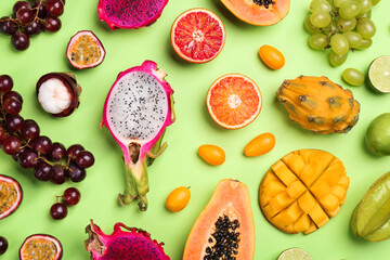 Many different delicious exotic fruits on green background, flat lay