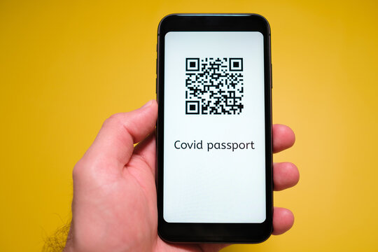 A Smartphone With Electronic Immune Digital Health Passport, Covid Pass With QR Code In Mans Hand On The Yellow Background.