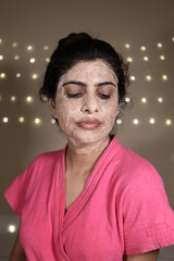 Beautiful Indian Lady in Pink Bathrobe with face pack on the face giving different expressions