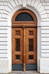 Details of European style classic old-fashion elegant wood carving door panels made of wood and decorated with wrought iron at a white concrete building in Rome, Italy