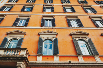 Low angle shot showing details of European classic building with beautiful Italian architectural style window panels located on street of Rome in Italy