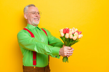 Profile side photo of aged man happy positive smile flowers bouquet birthday gift isolated over yellow color background