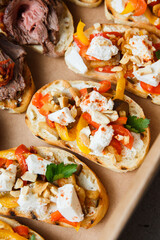 
A set of different snacks for a party or a festive table. Ciabatta sandwiches with tomatoes, jamon, cream cheese, vegetables, chambers and olives. Delicious wine snacks