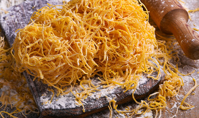 Tagliatelle pasta is thin. Traditional Italian named Angel Hair , capellini d'angels. Italian egg pasta, homemade and fresh in flour on a cutting table. 