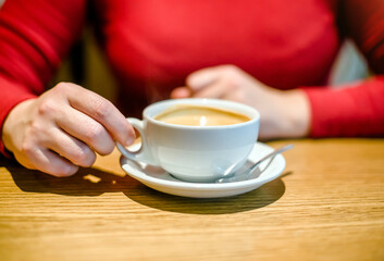 A girl drinks coffee at a table in a cafe
