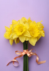 Beautiful daffodil bouquet on violet background, top view