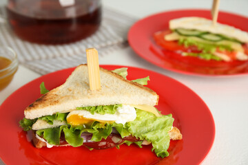 Delicious sandwich with vegetables, egg and salami on white table, closeup
