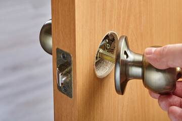 Repairing of door knob with latch and lock, in living room.