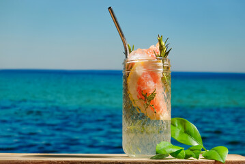 Summer drinks, beach cocktail party. Glass of hard seltzer cocktail, blue sea on background. Summer resort concept.