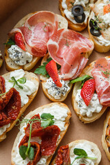 
A set of different snacks for a party or a festive table. Ciabatta sandwiches with tomatoes, jamon, cream cheese, vegetables, chambers and olives. Delicious wine snacks
