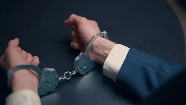 Arrested criminal businessman in handcuffs in the interrogation room. Arrest of the offender. Detention and interrogation of the accused man.