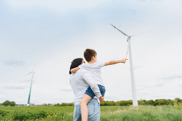 Mother holding her son in nature. Wind turbines in the background.