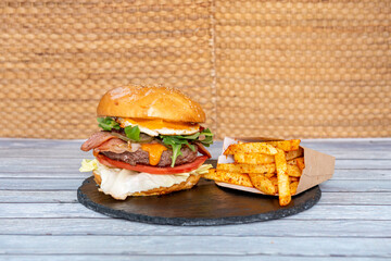 formidable beef burger with egg, bacon, arugula, tomato, lettuce and a portion of potatoes