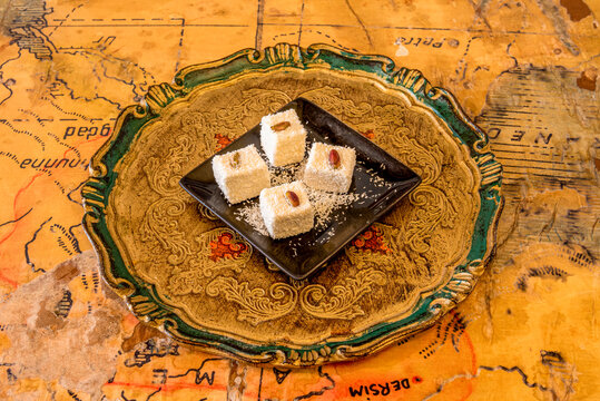 Four pieces of turkish delight with pistachio on top and sprinkled with coconut scratch