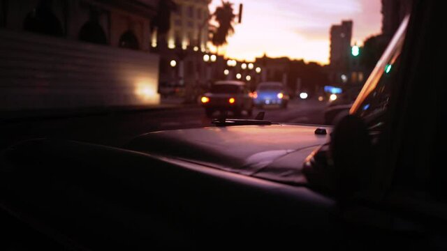 Dramatic cinematic sunset clip on the streets of Havana as the sun goes down and rows of vintage taxis drive past. 