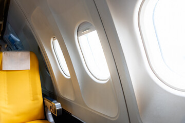 Airplane window with yellow color empty airplane seat.