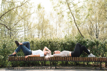 Two young women having a rest outdoors. Girlfriends lying on a bench in the city garden. Happy...
