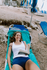 Woman sunbathing and reading at the beach at the ocean