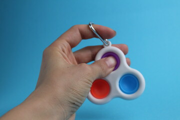 toy anti-stress popit simple dimple in hand on a blue background