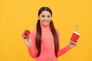 happy teen girl with takeaway coffee cup and apple on yellow background, lunch
