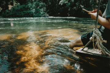 young cute Japanese hipster girl relaxing at beautiful lake view sitting river jungle mountains green forest at Phetchaburi, Kanchanaburi, Thailand. guiding idea women backpacker