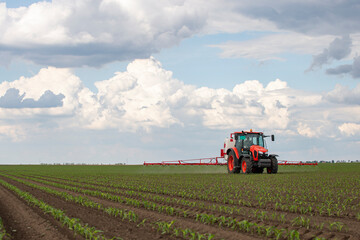 Fototapeta na wymiar Tractor spraying pesticides at corn fields