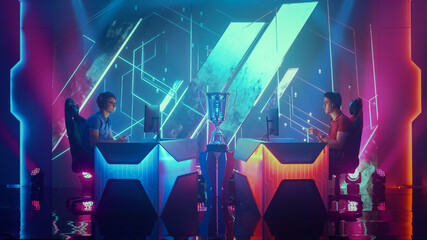 Two Professional Esport Gamers Using Controllers Playing Console Video Games on a Championship Event with Big TV Screens and Stylish Neon Arena. Global Online Streaming Cyber Gaming Tournament © Gorodenkoff