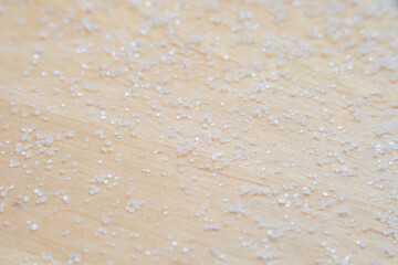 Background with salt scattered on a wooden surface. Close-up of blurry salt granules in soft focus...