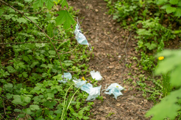 Protective medical masks in the forest. Disposed of as garbage masks polluting nature. Environmental pollution caused by the right things.