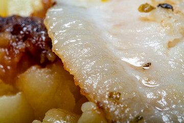Fried fish in oil with herbs and spices with homemade fried potato. Simple, homemade food. Close-up of a blurry potato and fish at high magnification