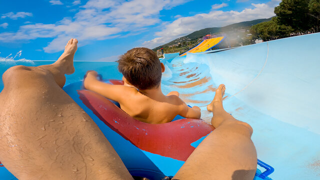 Adult And A Boy Sliding Down A Water Slide Of A Water Amusement Park, From Personal Perspective, First Point Of View.